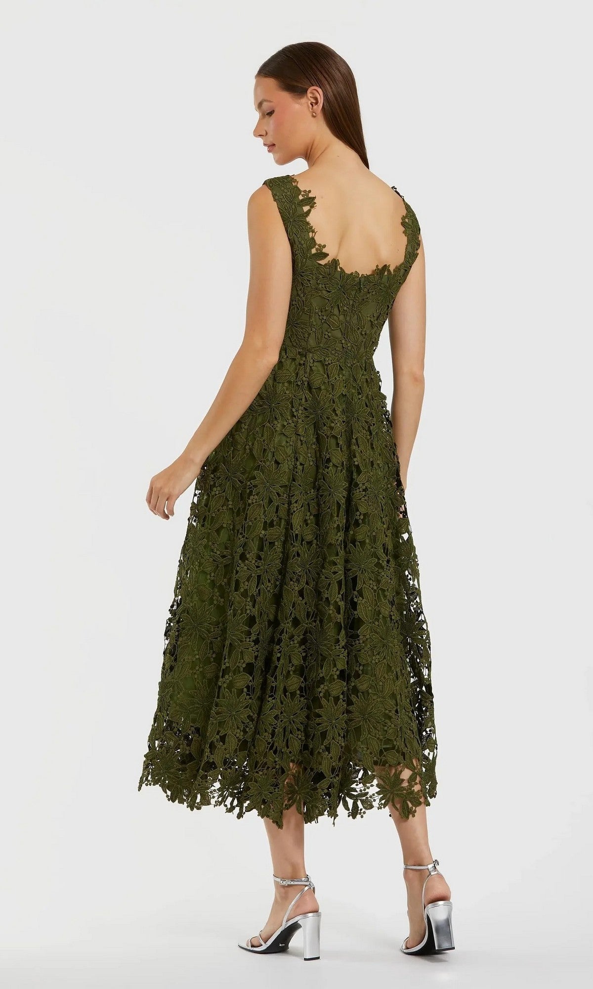 A woman stands on a plain light background in silver high-heeled sandals, wearing the Midi Party Dress: Mac Duggal 69073—a sleeveless, green floral lace A-line midi dress with a scalloped hem that exudes sophistication and charm.